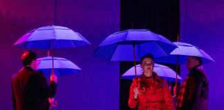 Actors on stage with umbrellas