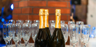 A pair of champaign bottles and a lot of flutes