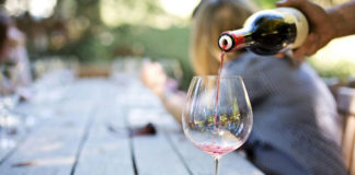 Traditional vs. Digital Marketing for Wineries and Vineyards Someone pouring a glass of red wine into stemware.