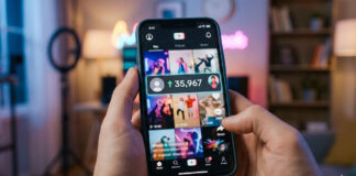 Person holding a smartphone showing a short-form video feed with creator content and a visible increase in followers, in a softly lit indoor setting.